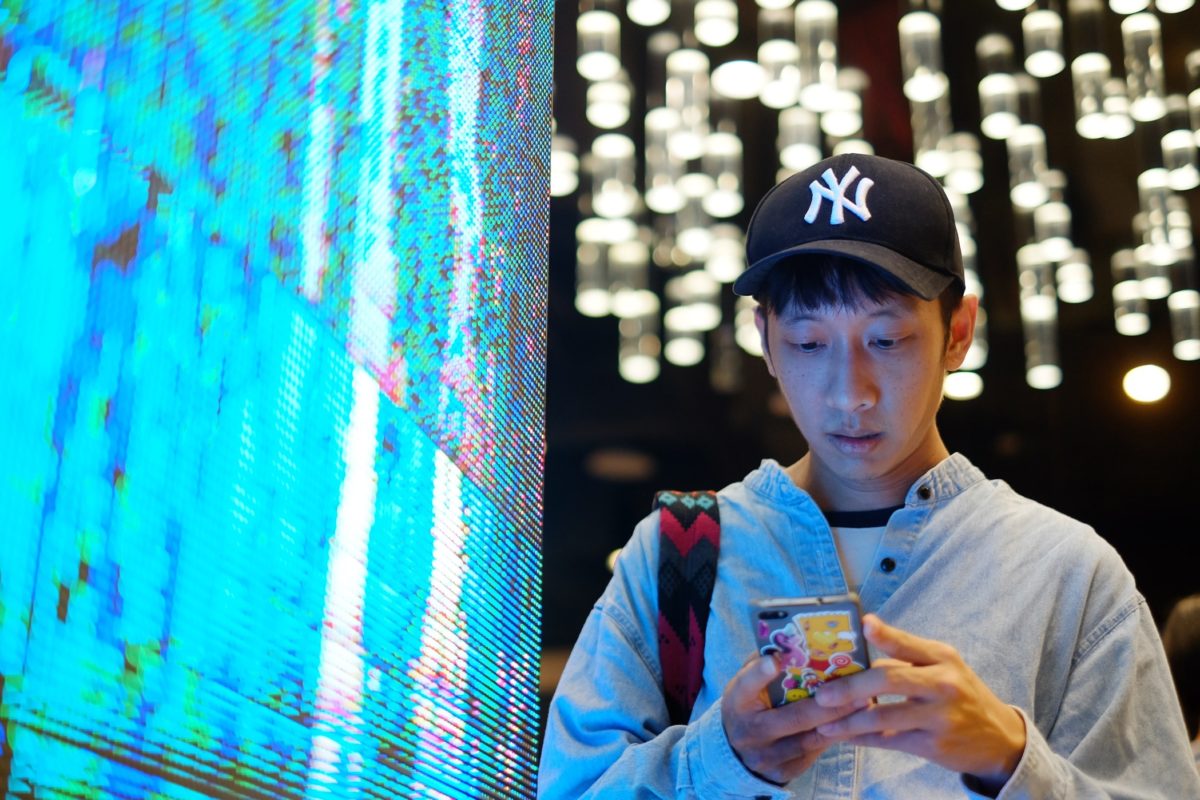 Young man using smartphone at the neon LED light screen